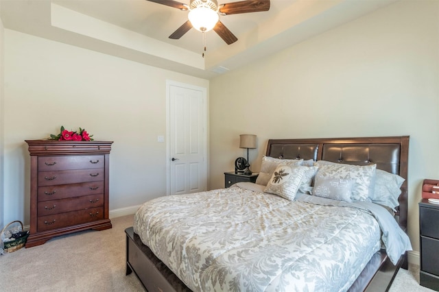 bedroom featuring baseboards, a raised ceiling, a ceiling fan, and light colored carpet