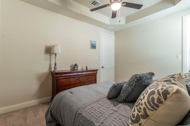 bedroom with baseboards, visible vents, ceiling fan, a tray ceiling, and carpet floors