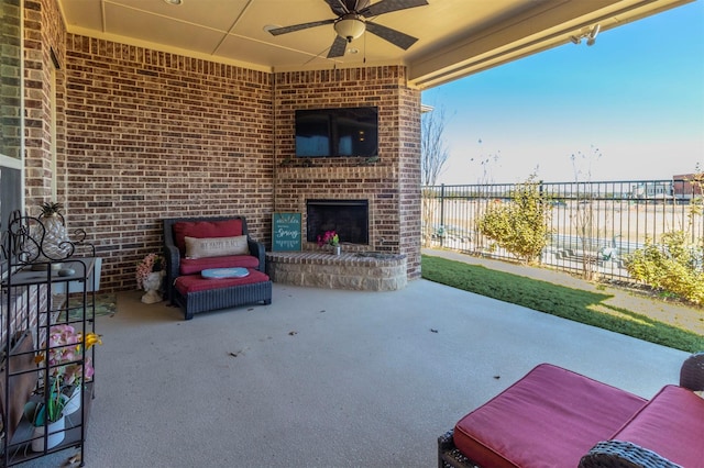 view of patio / terrace with an outdoor brick fireplace, ceiling fan, and fence