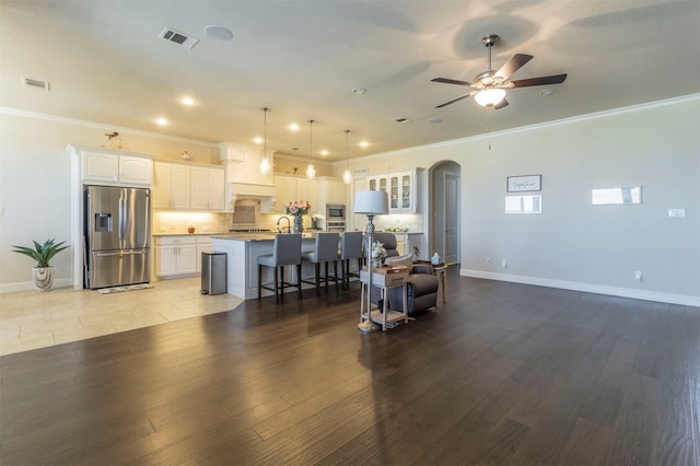 living area featuring light wood-type flooring, arched walkways, visible vents, and crown molding