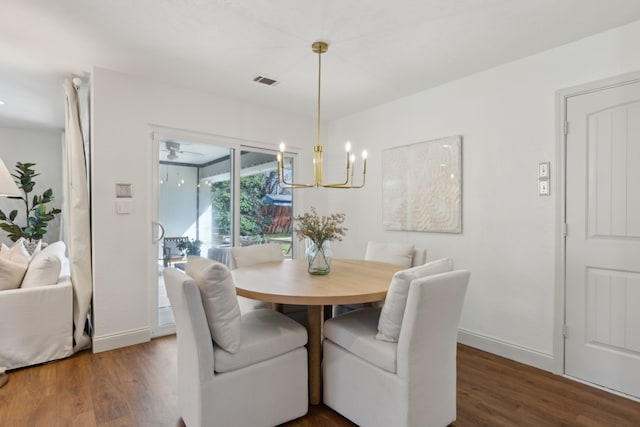 dining space with baseboards, wood finished floors, visible vents, and an inviting chandelier