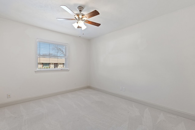 spare room featuring baseboards, a ceiling fan, and light colored carpet