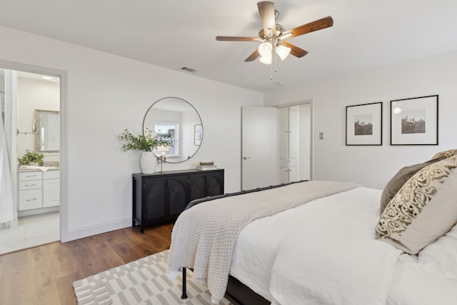 bedroom with baseboards, visible vents, connected bathroom, ceiling fan, and wood finished floors