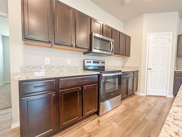 kitchen featuring baseboards, appliances with stainless steel finishes, light stone countertops, dark brown cabinets, and light wood-style floors