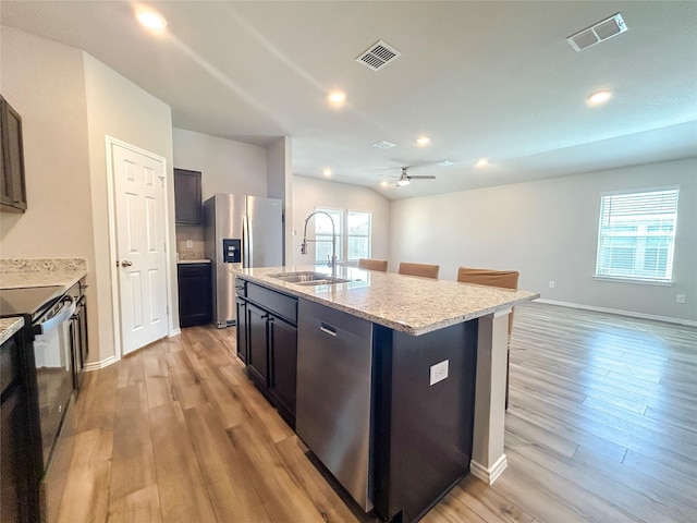 kitchen with stainless steel appliances, a sink, visible vents, light wood-type flooring, and an island with sink