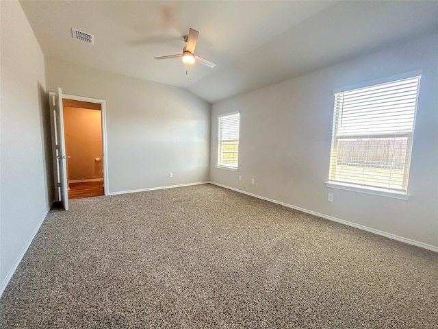 carpeted empty room featuring visible vents, vaulted ceiling, baseboards, and ceiling fan