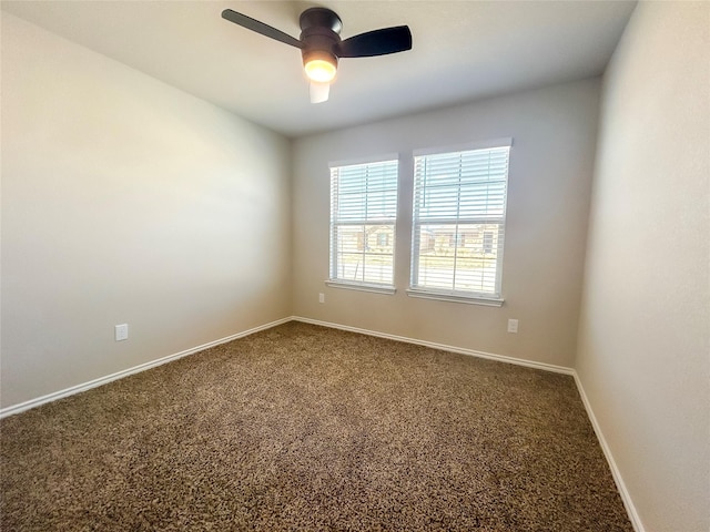 empty room featuring dark carpet, a ceiling fan, and baseboards