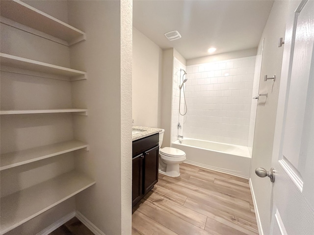 bathroom with shower / bath combination, visible vents, toilet, vanity, and wood finished floors