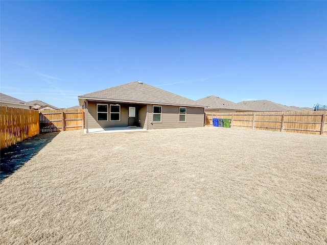 back of house with roof with shingles and a fenced backyard