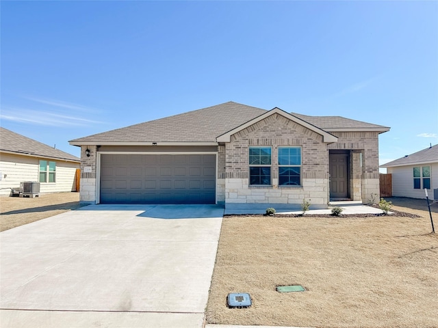 ranch-style house featuring driveway, a garage, roof with shingles, central AC, and brick siding