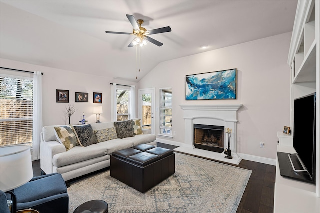 living room featuring a fireplace with raised hearth, a healthy amount of sunlight, dark wood-type flooring, and vaulted ceiling