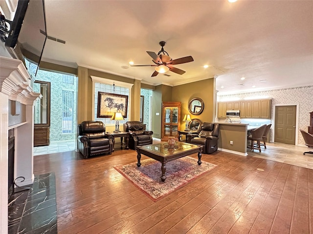 living room with crown molding, light wood-style flooring, and wallpapered walls