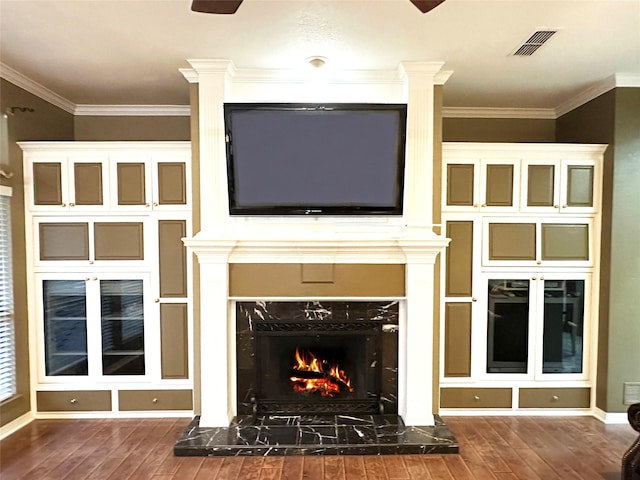 unfurnished living room with a fireplace, wood finished floors, visible vents, and crown molding