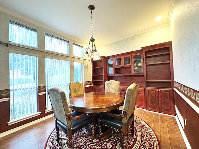 dining room with crown molding, light wood finished floors, and an inviting chandelier