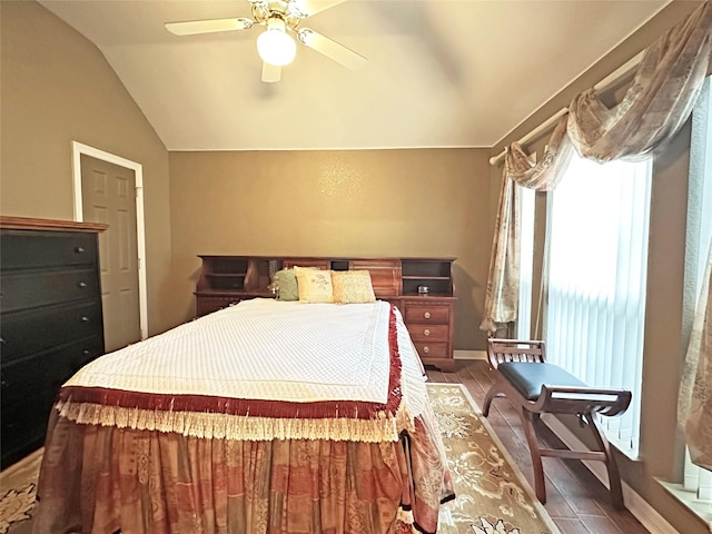 bedroom featuring a ceiling fan, vaulted ceiling, baseboards, and wood finished floors