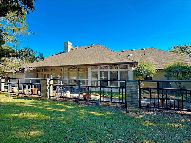 back of property with roof with shingles, a chimney, a lawn, a patio area, and fence