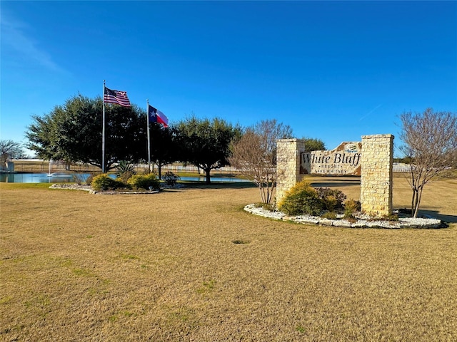 community sign featuring a water view and a yard