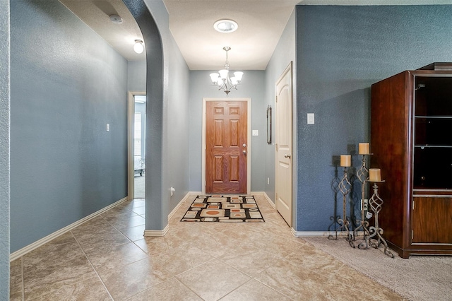 tiled entryway featuring an inviting chandelier, baseboards, and arched walkways