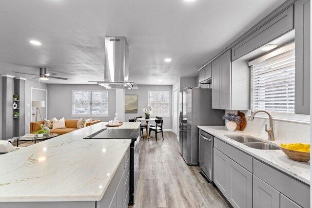 9723 Queenswood Ln, Dallas, TX 75238 - kitchen featuring stainless steel appliances, island range hood, a sink, light wood-style floors, and a wealth of natural light