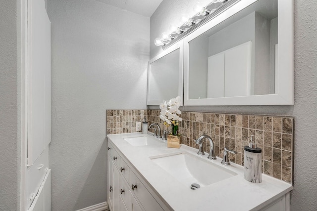9723 Queenswood Ln, Dallas, TX 75238 - bathroom with backsplash, a textured wall, a sink, and double vanity