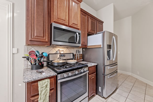 kitchen featuring appliances with stainless steel finishes, light stone countertops, baseboards, and tasteful backsplash