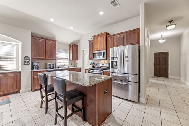 312 Salisbury Dr, Anna, TX 75409 - kitchen featuring appliances with stainless steel finishes, backsplash, light tile patterned flooring, light stone countertops, and vaulted ceiling