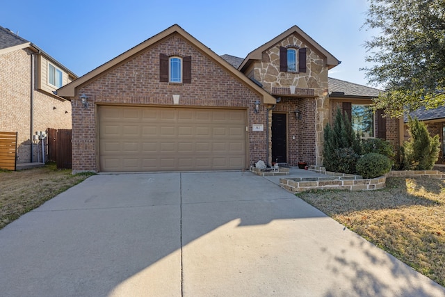 view of front of property featuring driveway, a garage, stone siding, fence, and brick siding