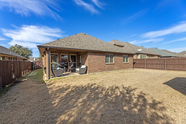 rear view of property with roof with shingles, a fenced backyard, a patio, and brick siding