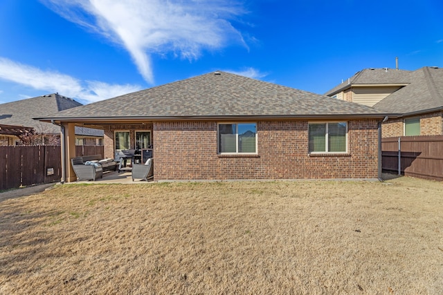 back of property with a shingled roof, brick siding, a patio, and a fenced backyard