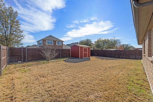 view of yard with a fenced backyard, an outdoor structure, and a storage unit