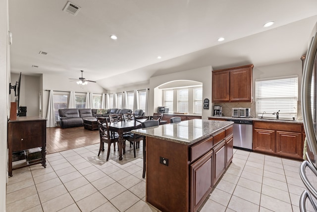 kitchen with light tile patterned floors, lofted ceiling, visible vents, stainless steel dishwasher, and decorative backsplash