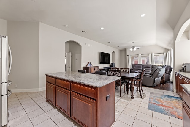 kitchen with freestanding refrigerator, a center island, visible vents, and light tile patterned floors