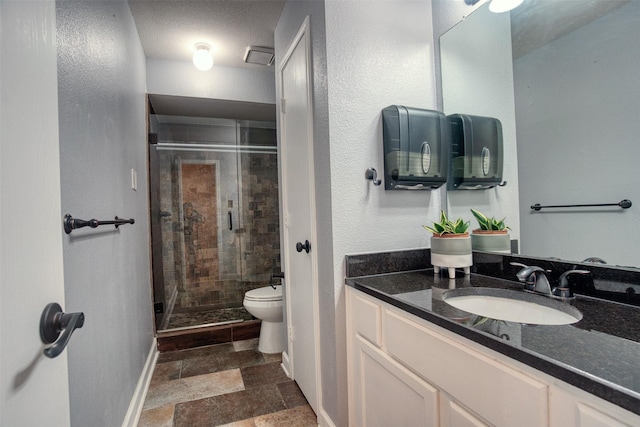 bathroom featuring stone tile flooring, toilet, a stall shower, vanity, and baseboards