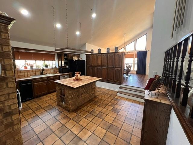 kitchen featuring a kitchen island, dark brown cabinets, black appliances, high vaulted ceiling, and a sink