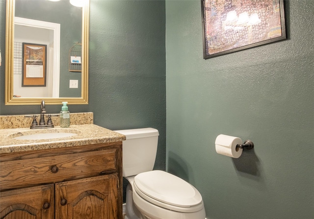 bathroom featuring a textured wall, vanity, and toilet