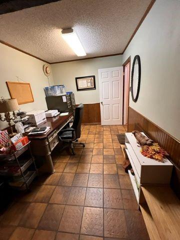 office featuring wood walls, crown molding, a textured ceiling, and wainscoting