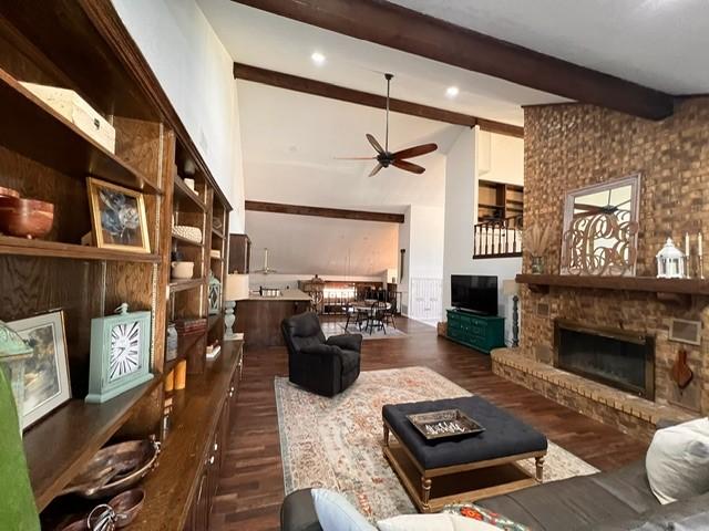 living room featuring ceiling fan, dark wood-type flooring, a fireplace, beam ceiling, and recessed lighting