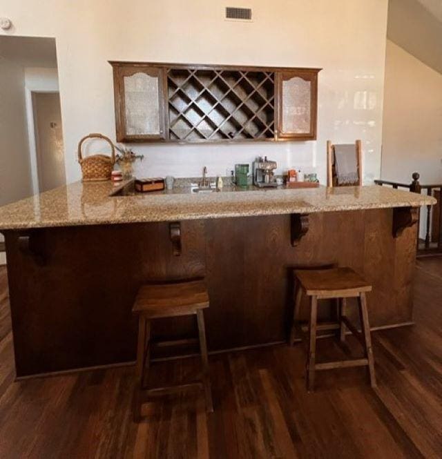 bar with dark wood-type flooring, indoor wet bar, and visible vents