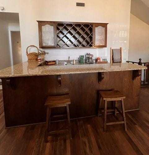 bar with dark wood-style floors, wet bar, and visible vents