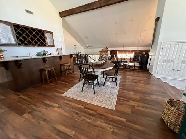 dining room featuring high vaulted ceiling, dark wood-type flooring, visible vents, beamed ceiling, and indoor wet bar