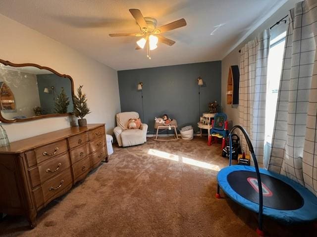 playroom with a ceiling fan and carpet