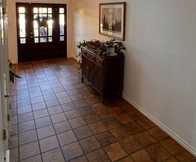 foyer entrance featuring baseboards and tile patterned floors