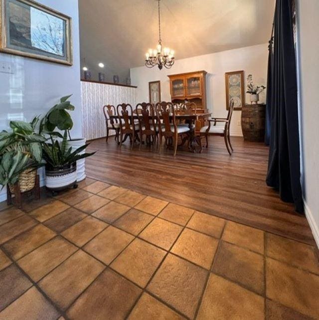 dining area with a chandelier, lofted ceiling, and wood finished floors