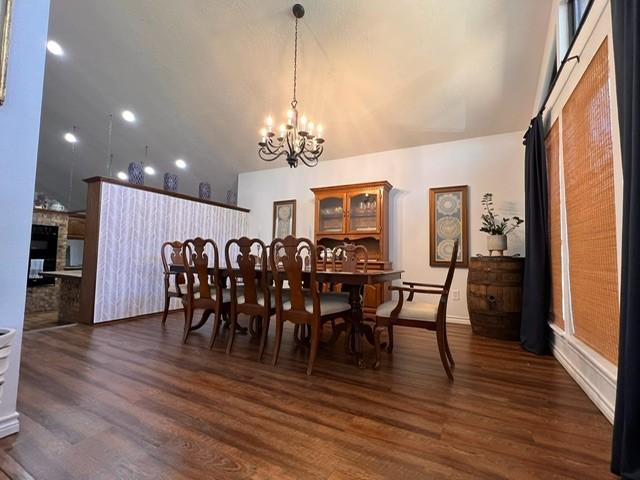 dining room with dark wood-style floors, a high ceiling, a fireplace, and a notable chandelier