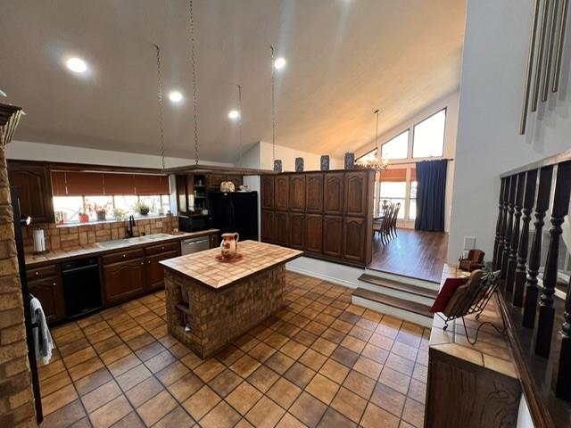 kitchen featuring a chandelier, dark brown cabinetry, a kitchen island, a sink, and black appliances