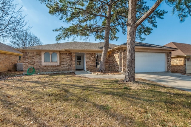 ranch-style home with an attached garage, central air condition unit, brick siding, concrete driveway, and a front yard