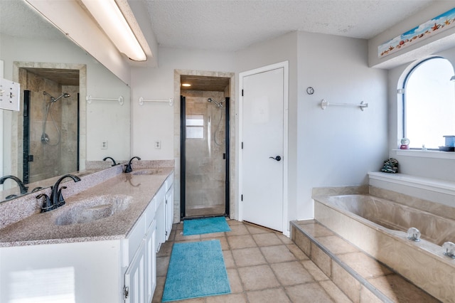 bathroom with a textured ceiling, a sink, a garden tub, and a shower stall