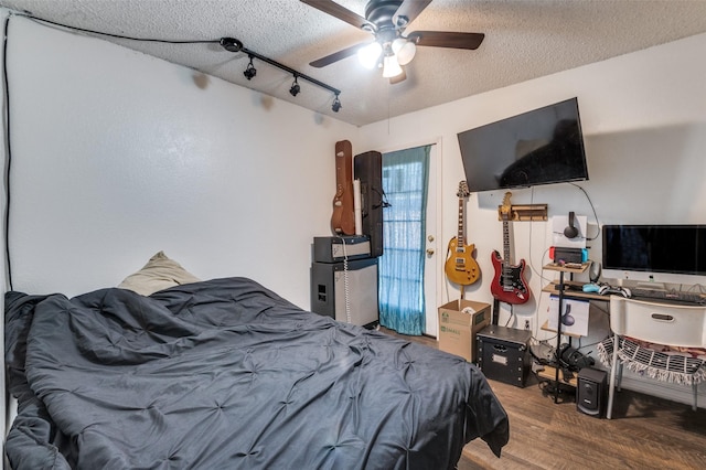 bedroom featuring arched walkways, a ceiling fan, wood finished floors, rail lighting, and a textured ceiling