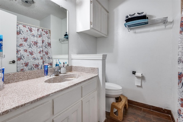 full bath with a textured ceiling, toilet, wood finished floors, vanity, and baseboards