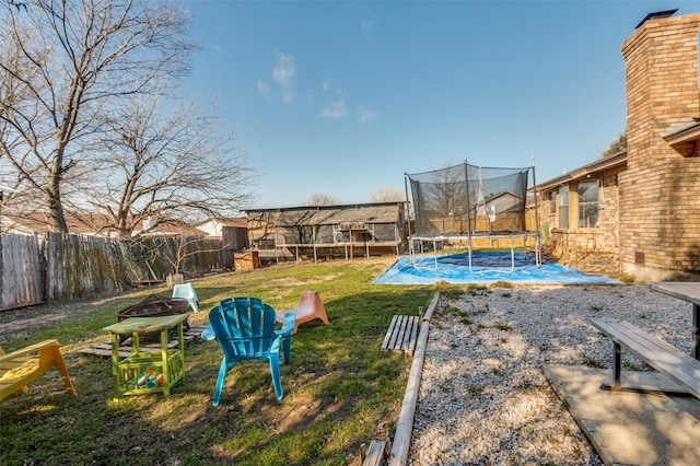 view of yard featuring a trampoline, an outdoor fire pit, and fence private yard